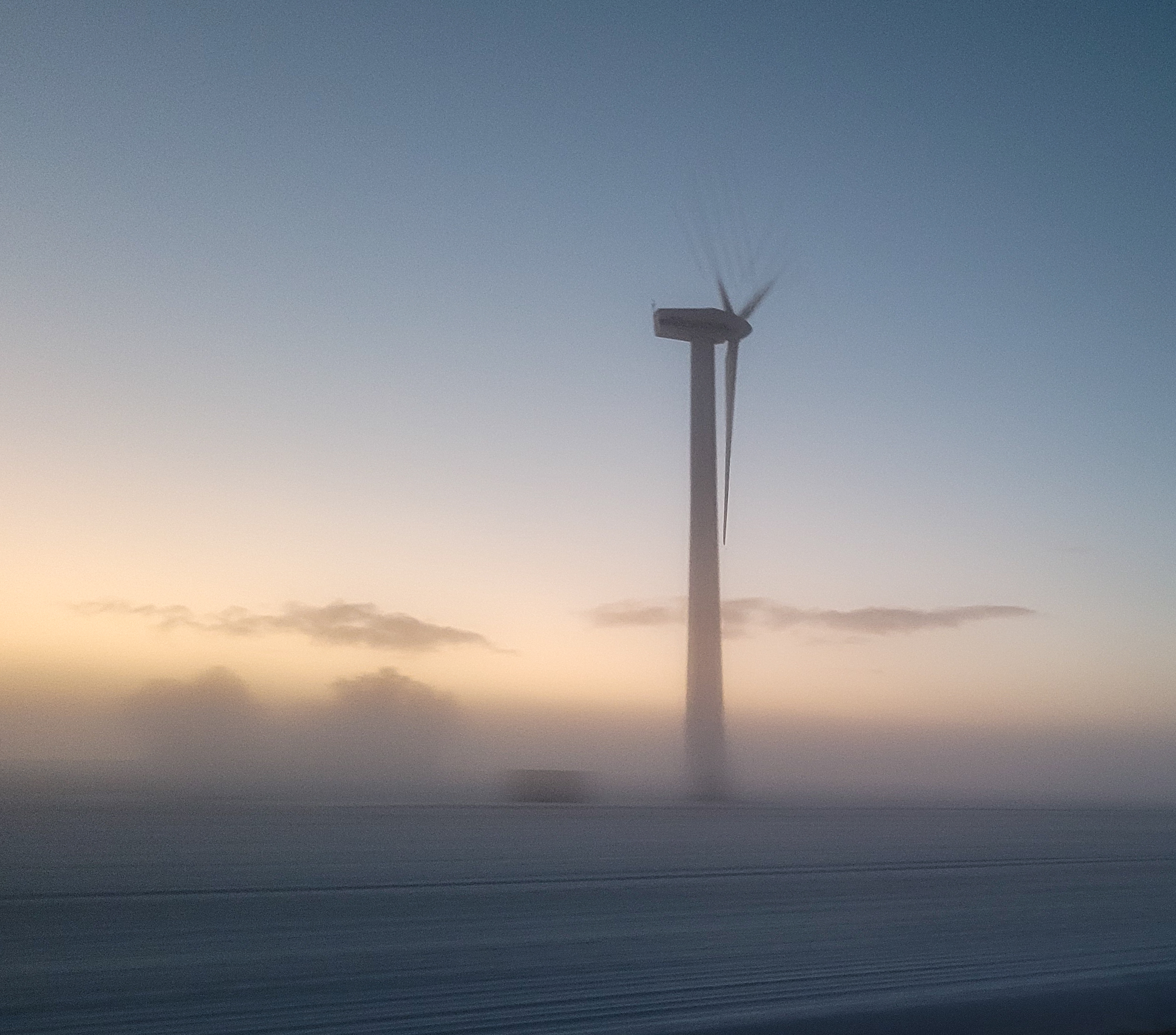 Windenergieanlage an Land im Nebel bei Sonnenuntergang